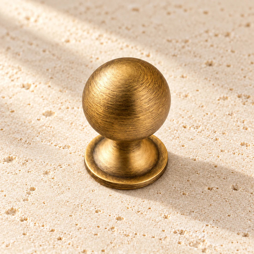 antique brass ball finial round knob limestone on pale limestone.