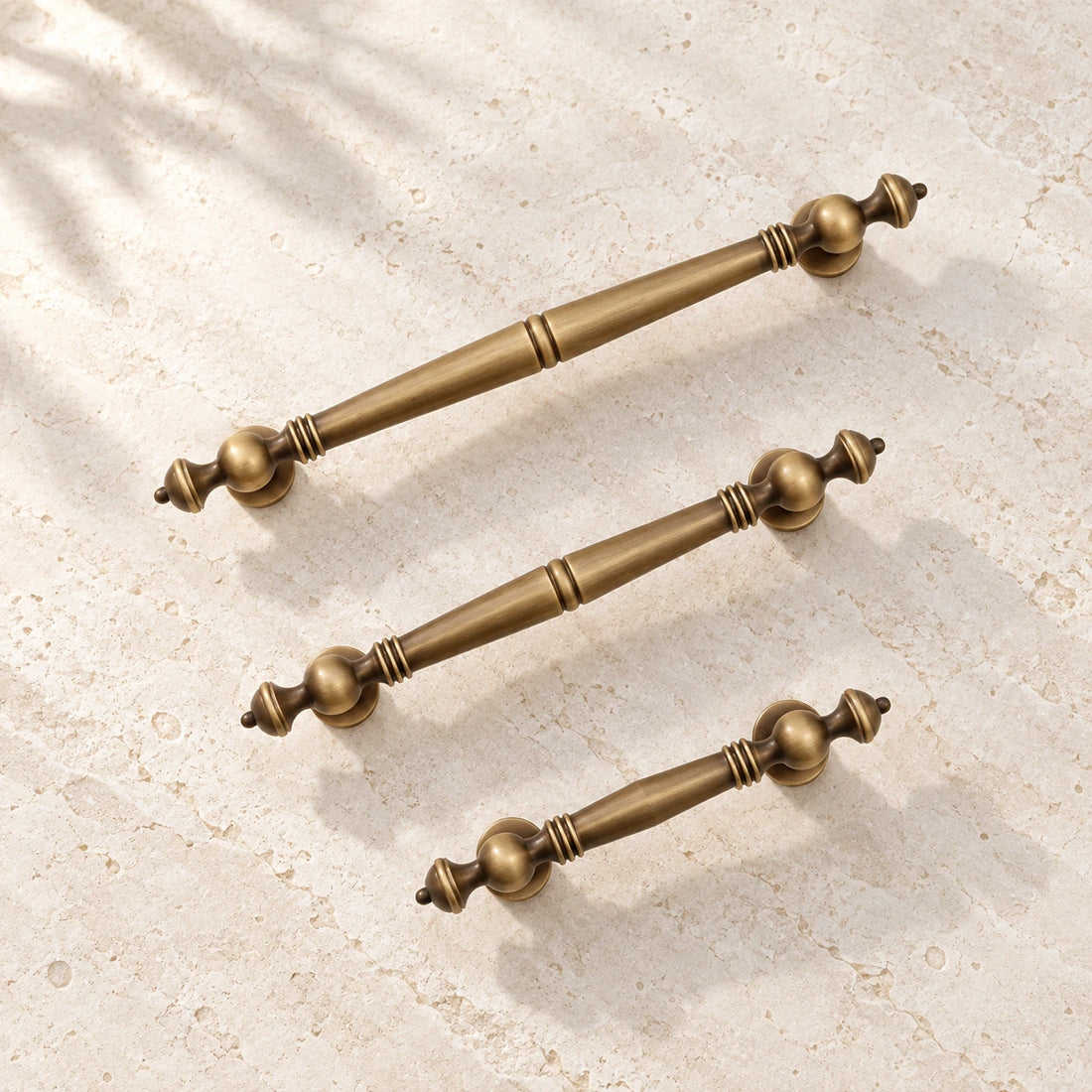 Antique brass baluster cabinet pulls on warm ivory limestone