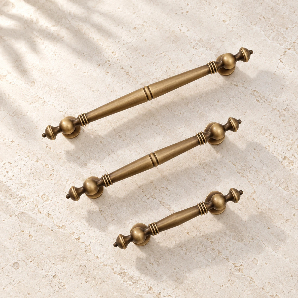 Antique brass baluster cabinet pulls on warm ivory limestone