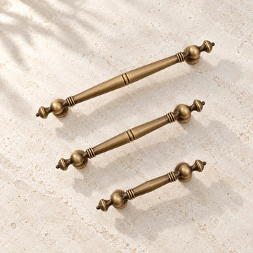Antique brass baluster cabinet pulls on warm ivory limestone