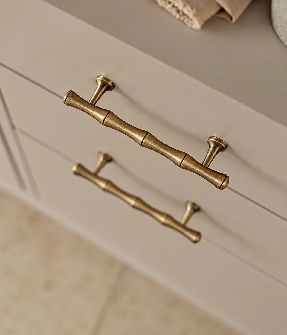 Antique brass bamboo cabinet pulls installed horizontally on cream drawers