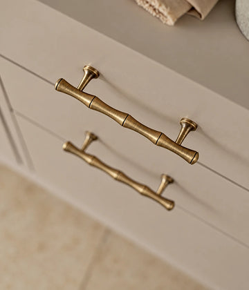 Antique brass bamboo cabinet pulls installed horizontally on cream drawers