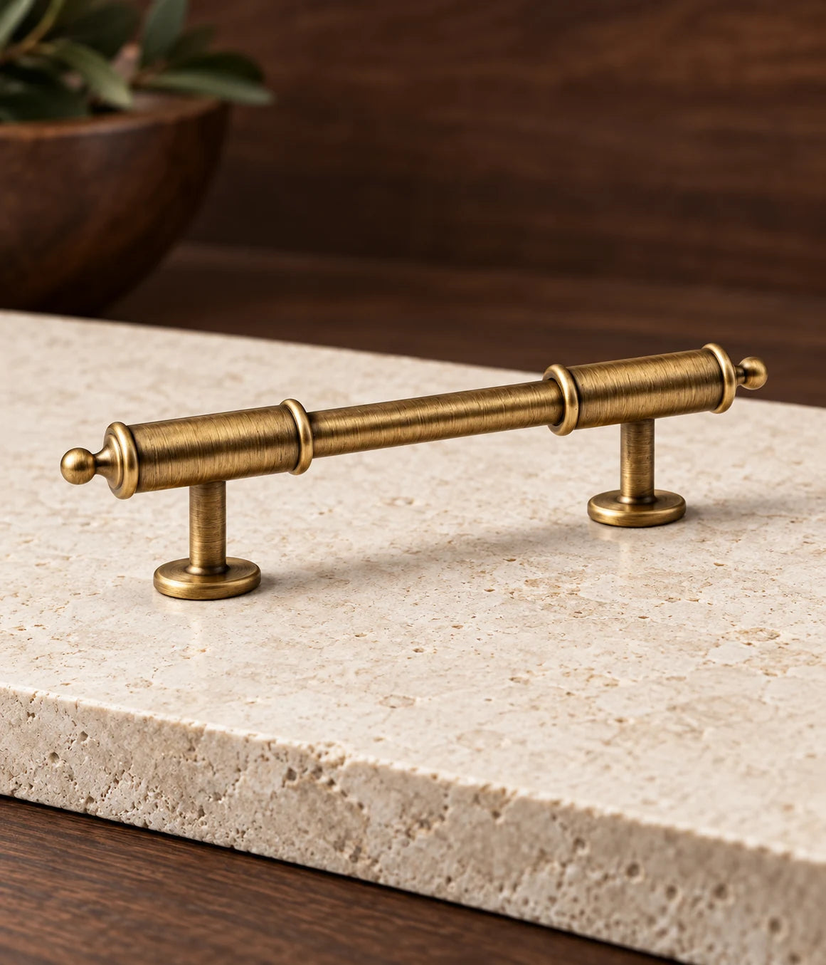 Detail of antique brass cabinet pull with long barrel collars, tiny ball tips and round mounting feet