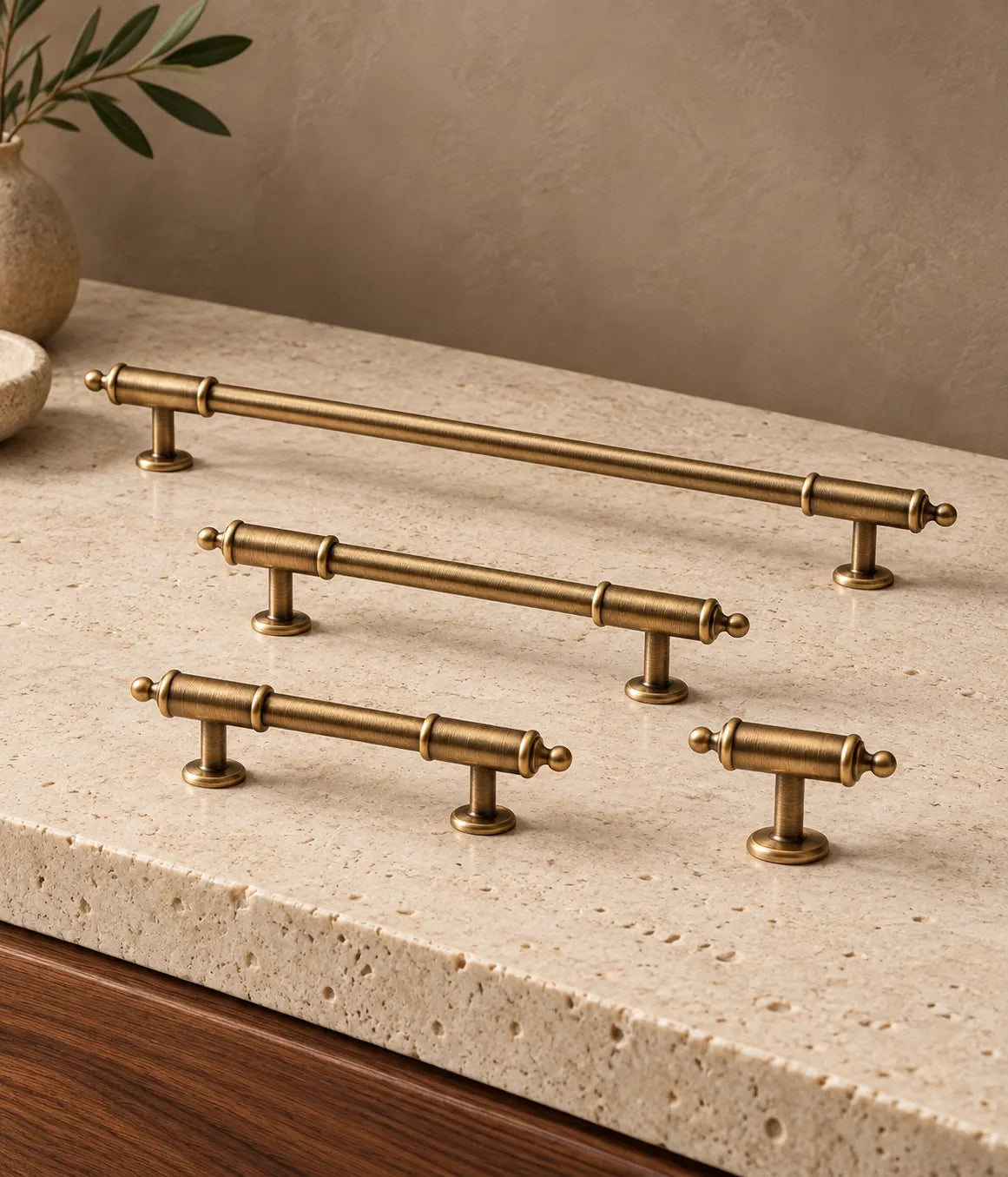 Antique brass barrel-collar cabinet pulls and matching ball-tip T-knob on pale limestone