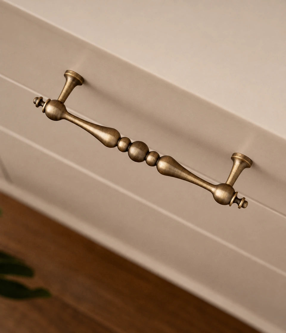 Beaded-center brass cabinet pull installed horizontally on a cream drawer