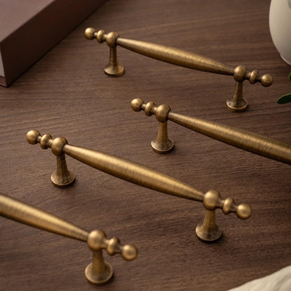 Close-up of antique brass tapered grips, beaded ends and flared mounting posts on wood