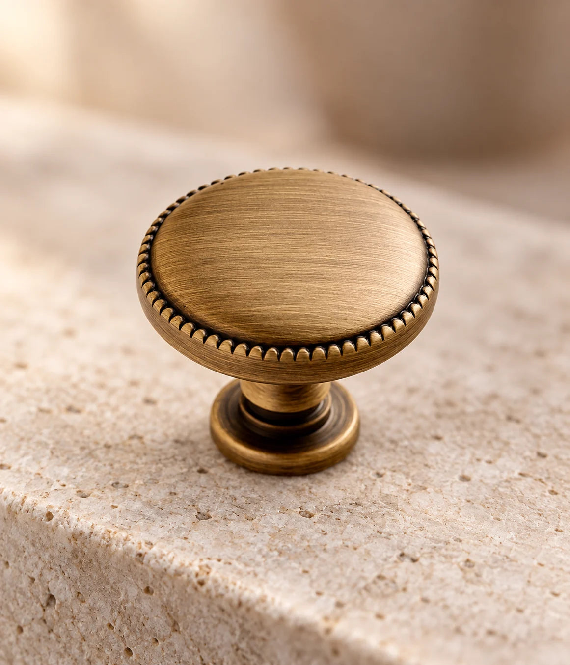 Antique brass cabinet knob showing its smooth disc face and fine beaded rim