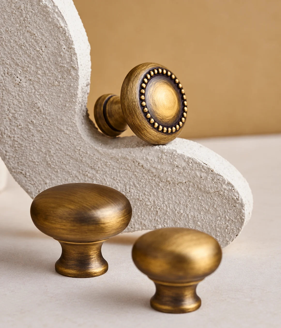 Close-up of antique brass beaded and smooth cabinet knobs on stone