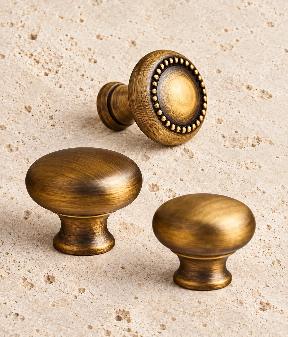 Antique Brass Beaded & Smooth Round Cabinet Knobs on warm limestone