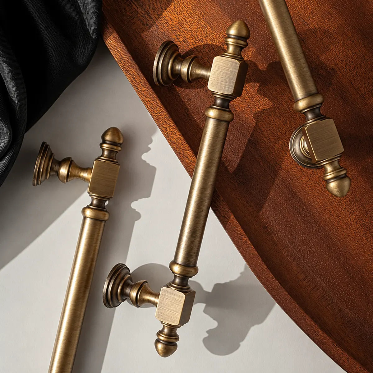 Brushed brass Block-End cabinet pulls beside a wooden tray and black cloth