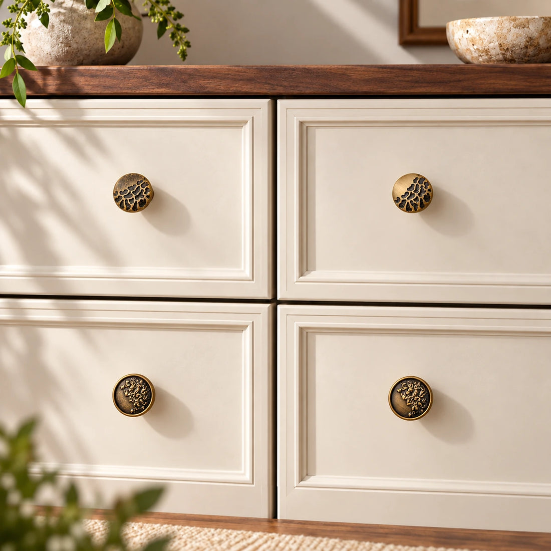Four antique brass botanical relief cabinet knob styles on a premium limestone background