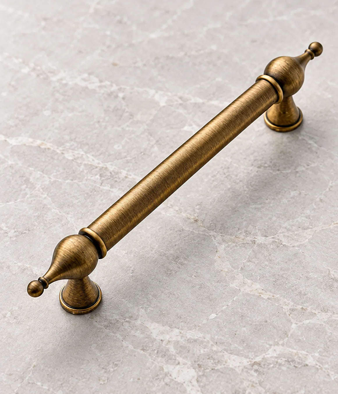 Close view of an antique brass pull with bulb finials and tapered round mounting bases