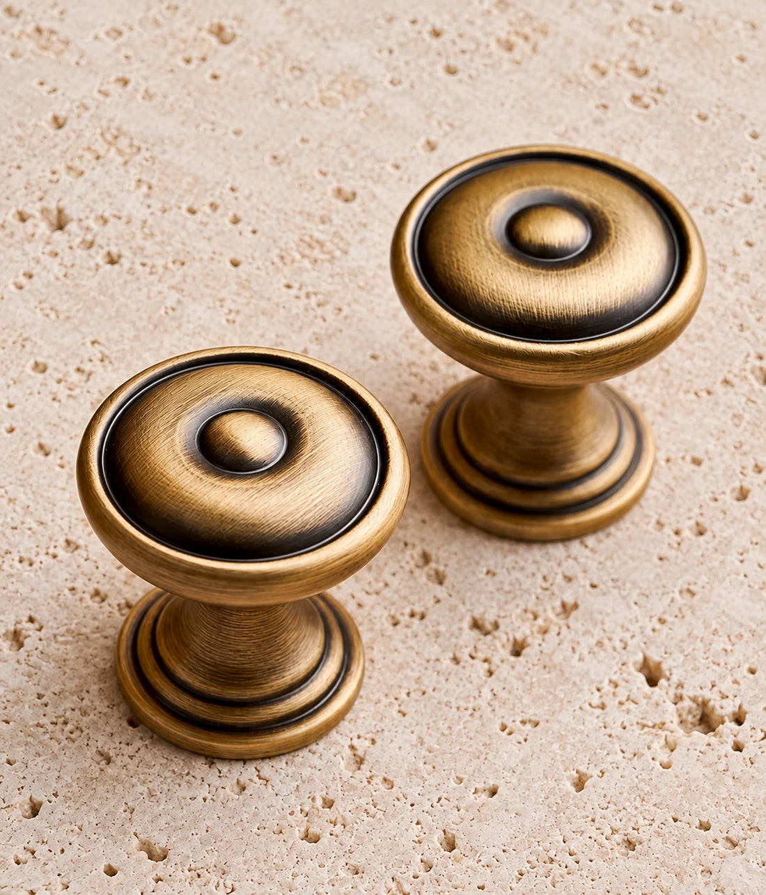 Antique Brass Bullseye Cabinet Knob on warm limestone