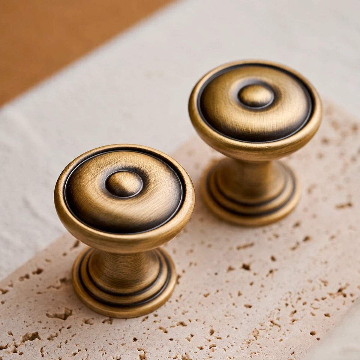 Raised centers and dark circular detailing on antique brass bullseye knobs