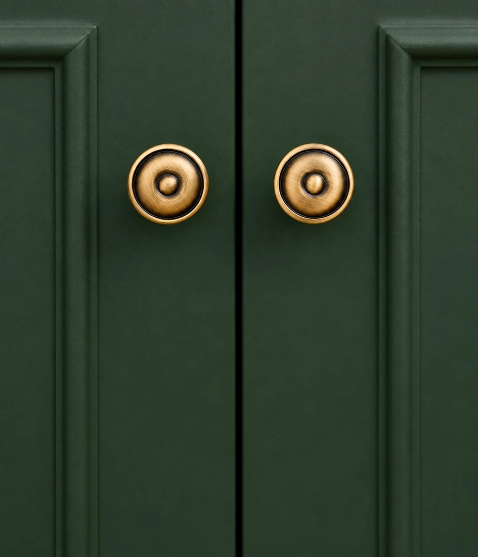 Antique brass bullseye cabinet knobs on dark green doors