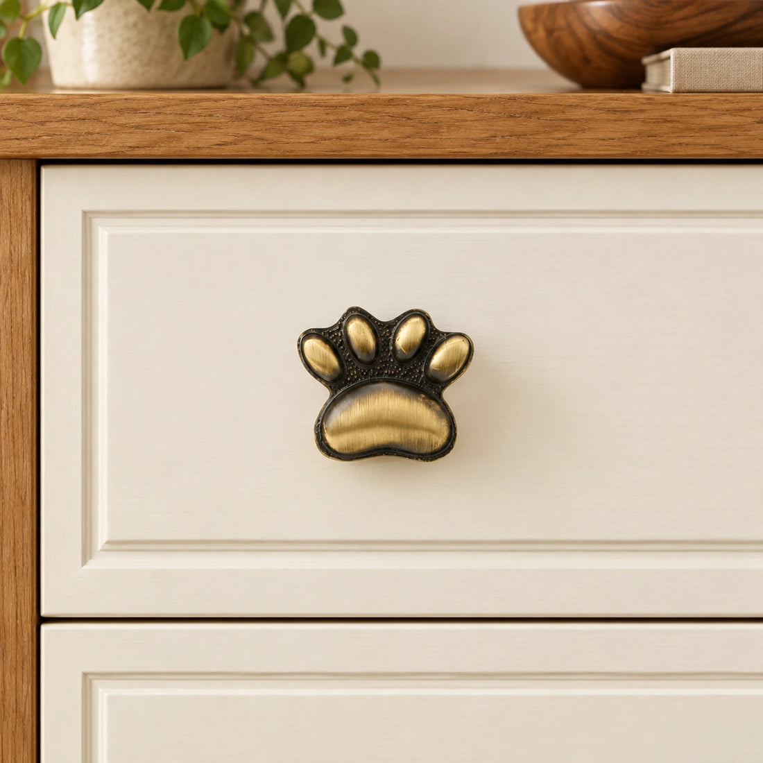 Antique brass cat paw cabinet knobs on limestone, showing the textured paw face and straight mounting stem