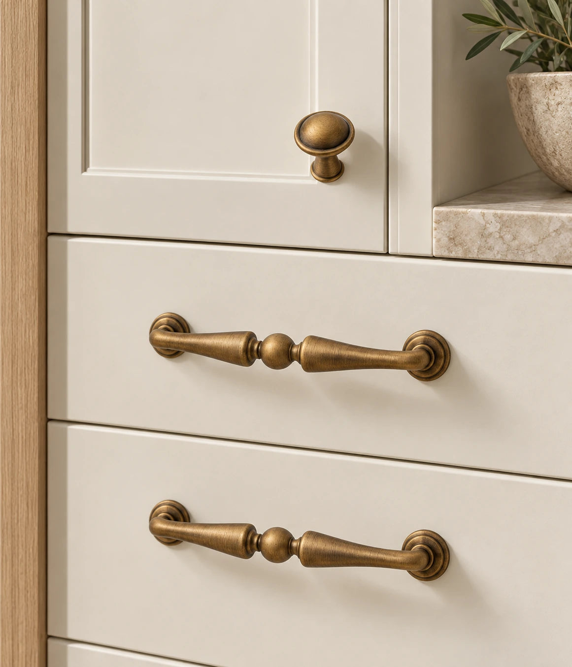 Antique brass center-ball pulls and domed knob on cream cabinetry