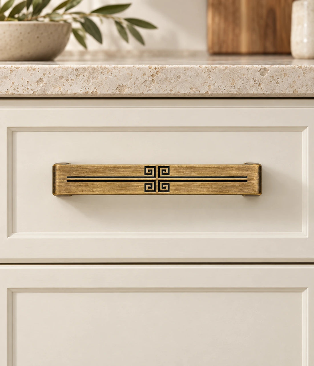 Antique brass cabinet pulls with central geometric engraving arranged on limestone