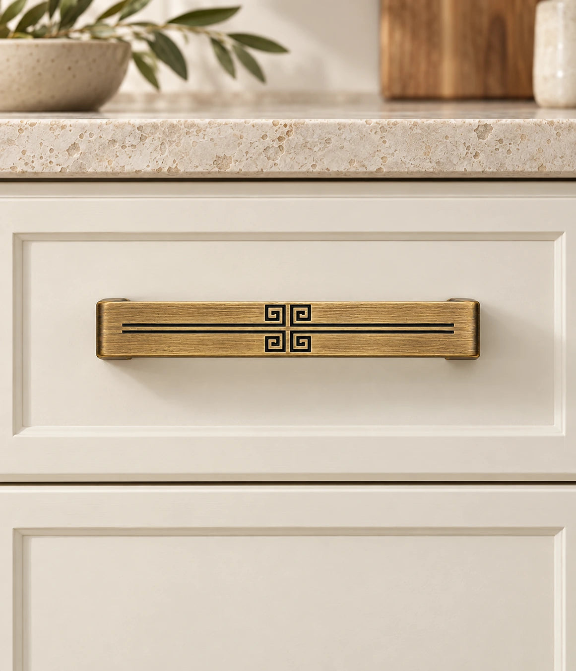 Antique Brass Central Geometric Cabinet Pulls installed on an ivory cabinet drawer