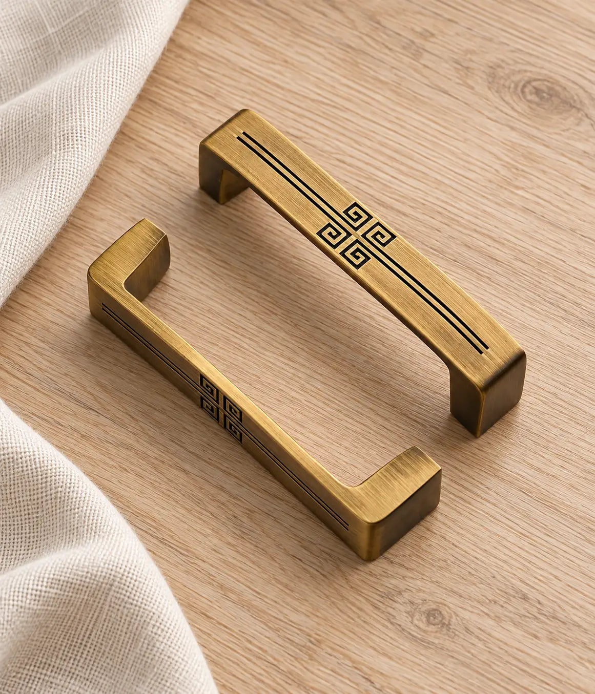 Antique brass geometric cabinet pulls styled on pale oak with natural linen