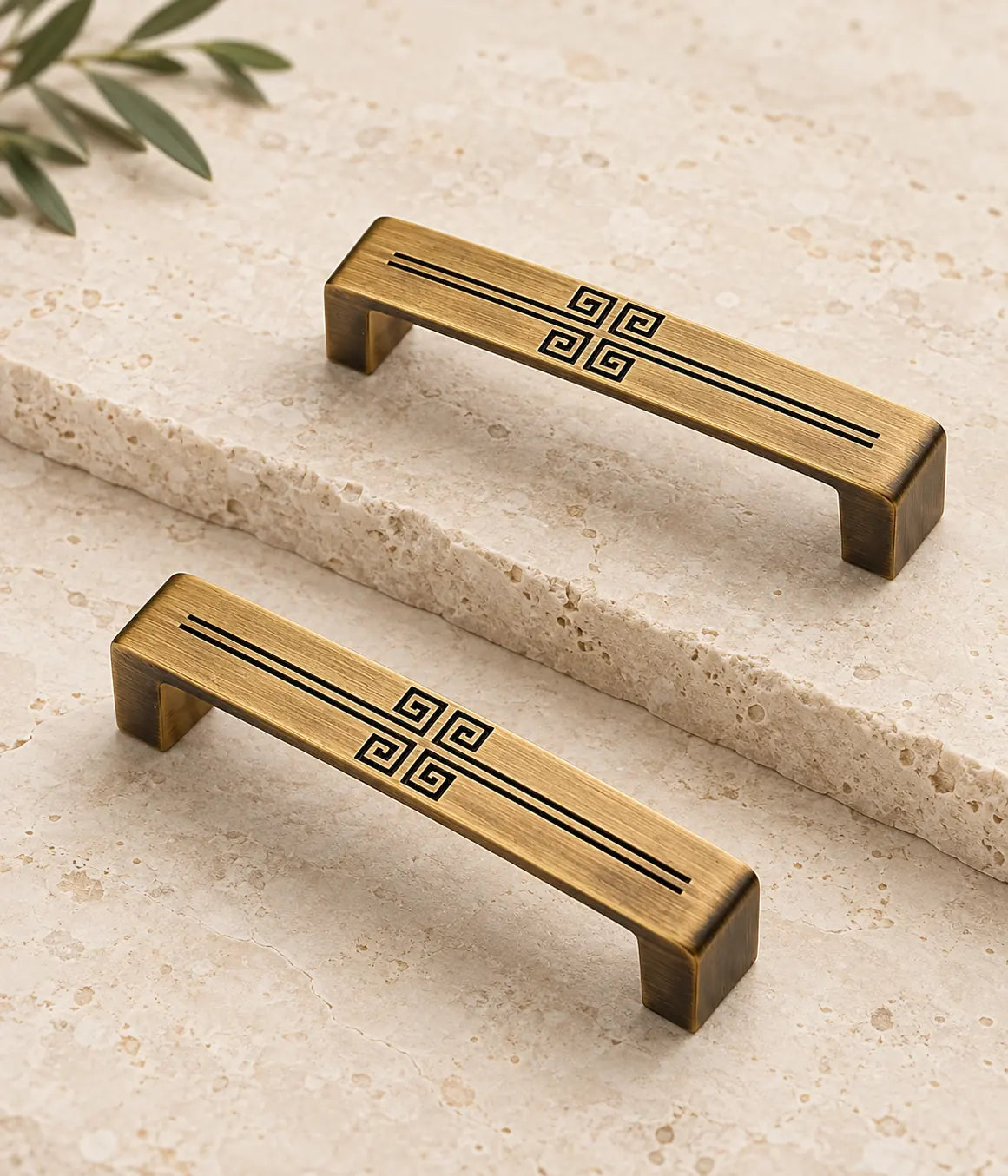 Antique brass cabinet pulls with central geometric engraving arranged on limestone