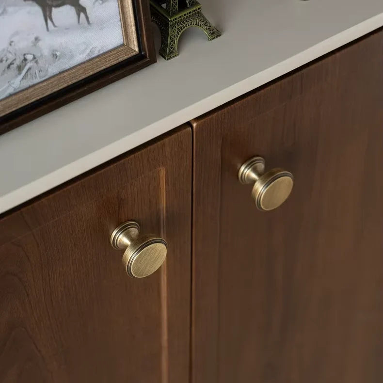 Round antique brass cabinet knobs fitted to wooden doors