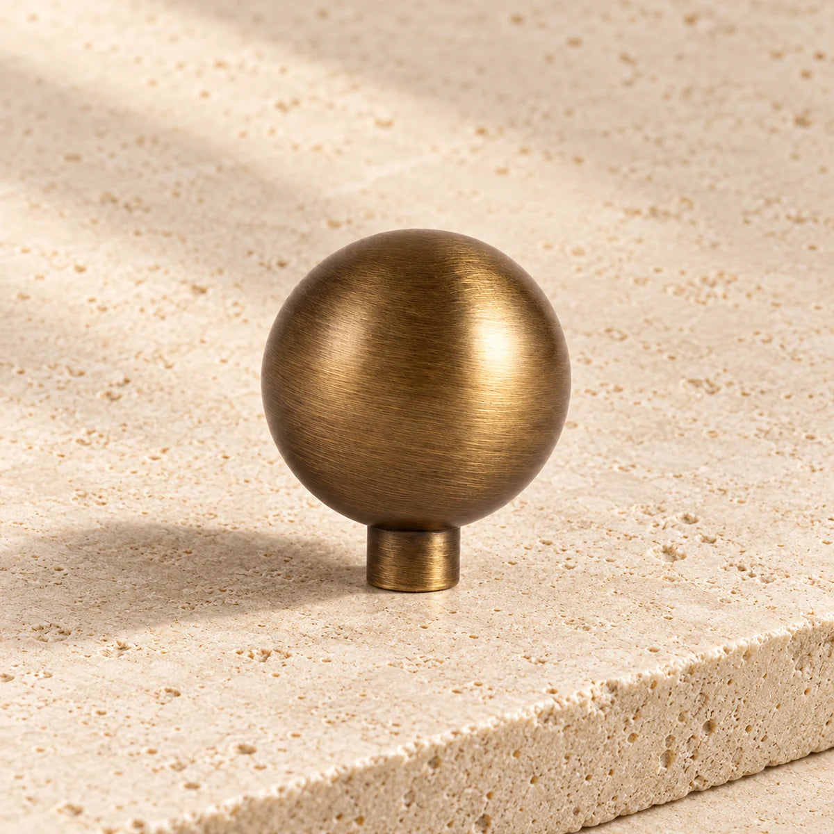 antique brass collared ball cabinet knob on pale limestone.