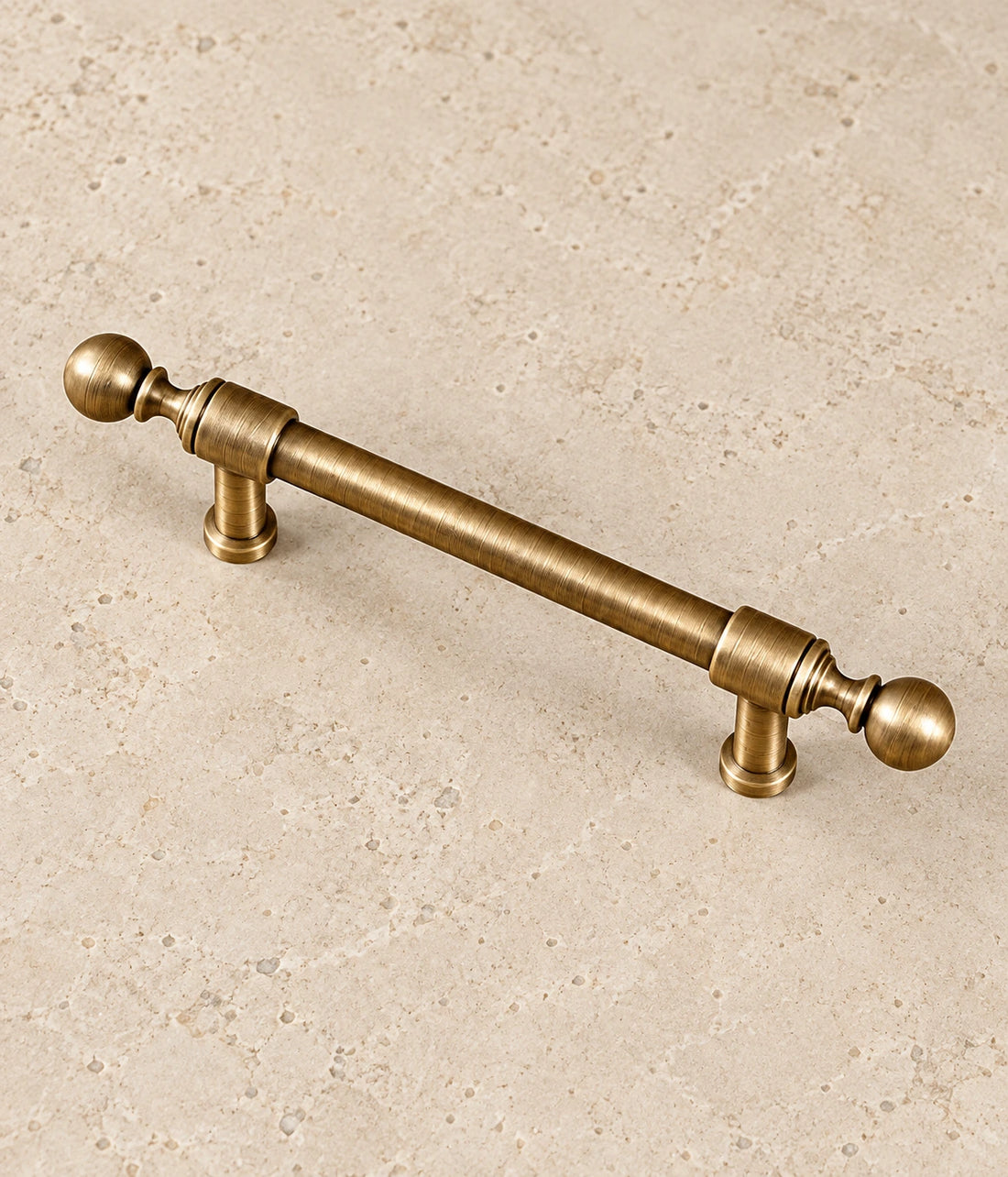 Antique Brass Collared Ball-End Cabinet Pulls & Knob on warm limestone
