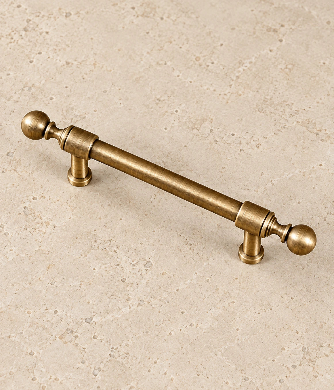 Antique Brass Collared Ball-End Cabinet Pulls & Knob on warm limestone