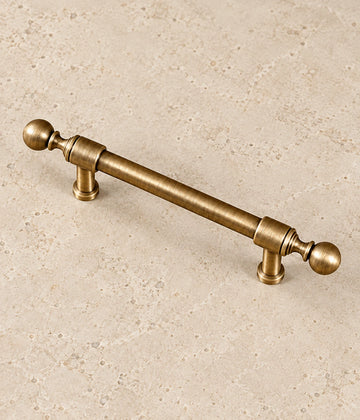 Antique Brass Collared Ball-End Cabinet Pulls & Knob on warm limestone