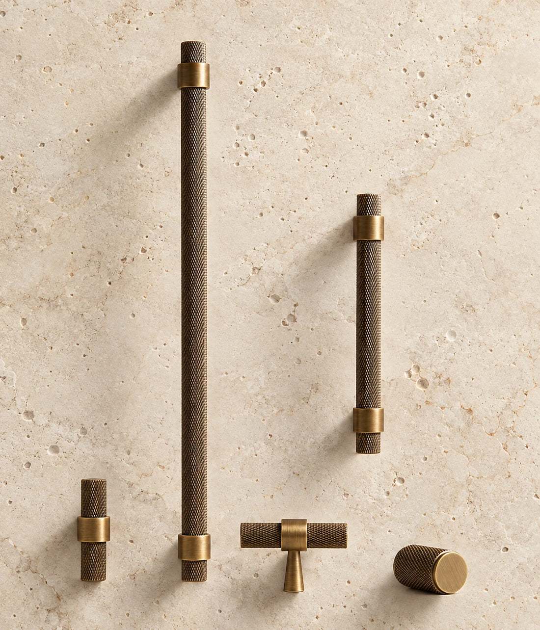 Antique Brass Collared Knurled Cabinet Pulls & Knobs arranged on warm limestone