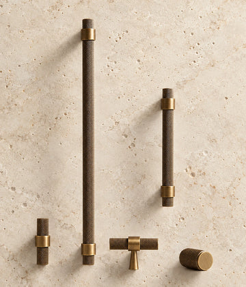 Antique Brass Collared Knurled Cabinet Pulls & Knobs arranged on warm limestone