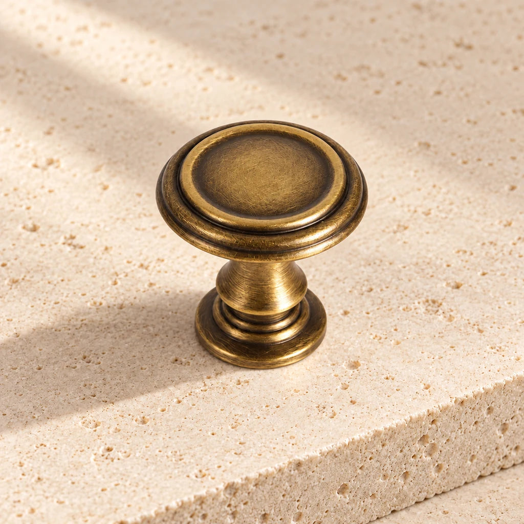 antique brass collared round knob on pale limestone.