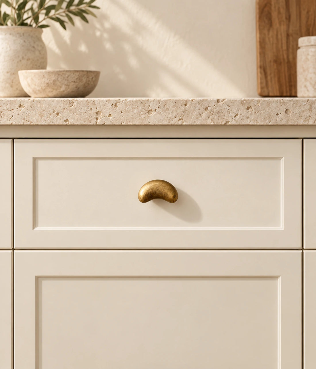 Antique brass crescent cabinet knobs arranged on ivory limestone