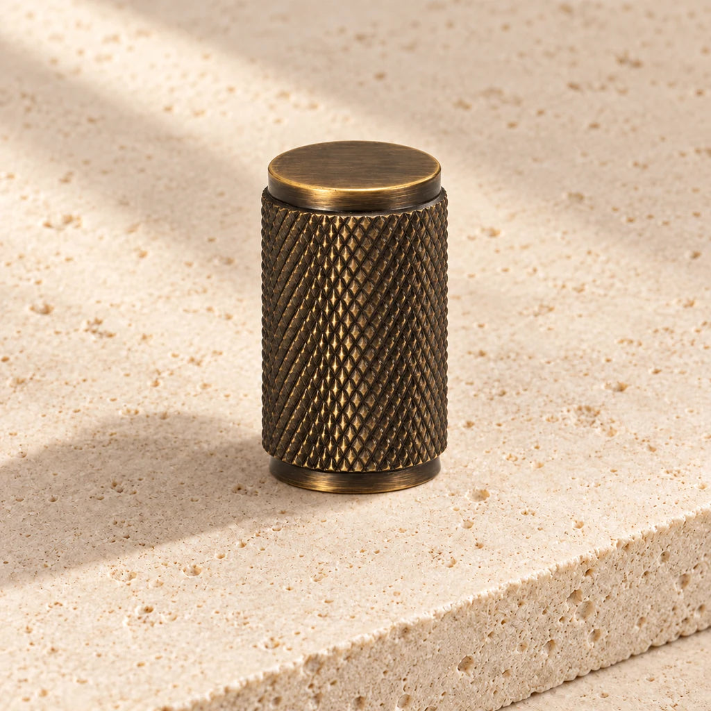 antique brass cross knurled cylinder knob on pale limestone.