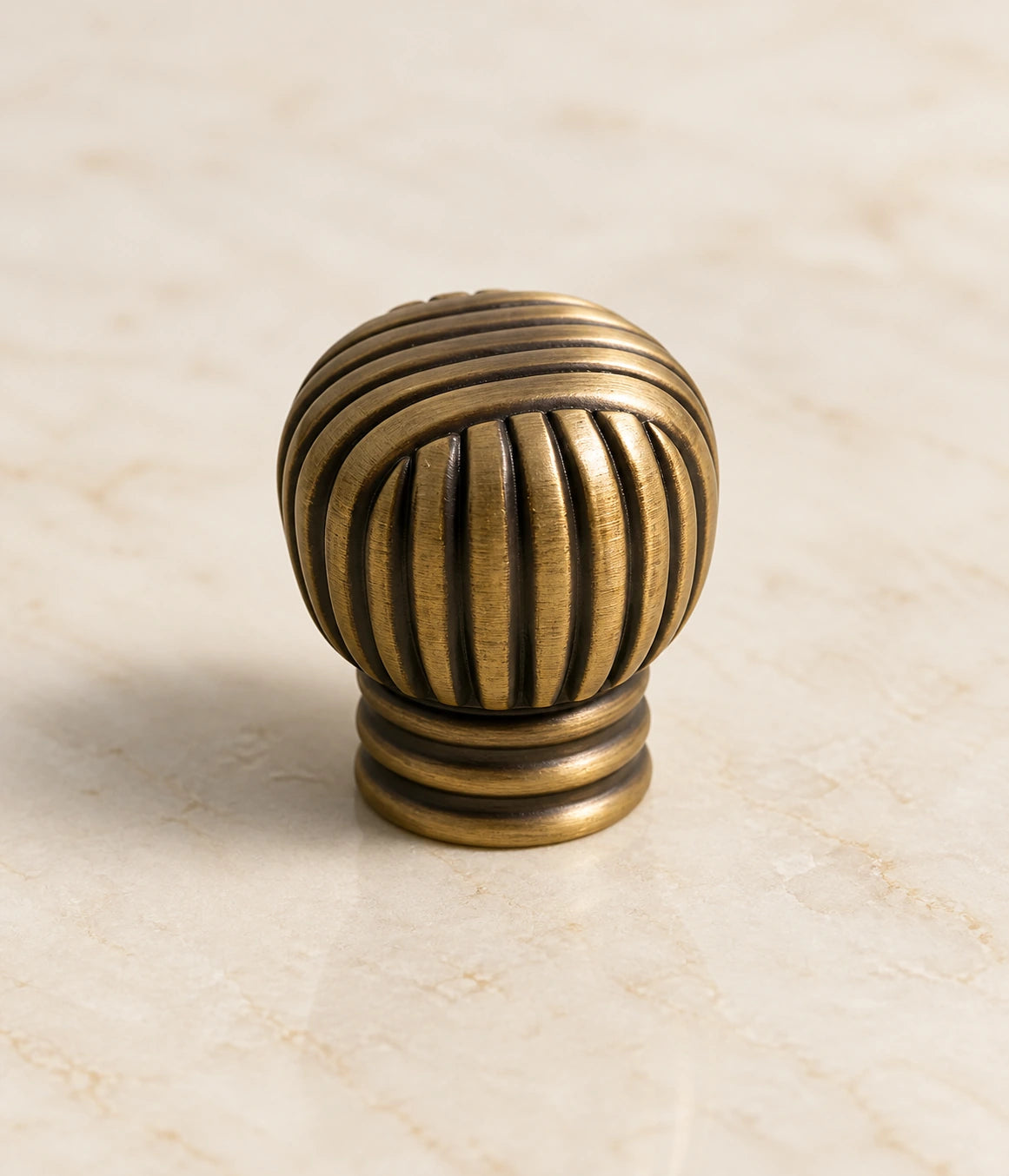Crossed rib pattern and ringed base of an antique brass ball knob