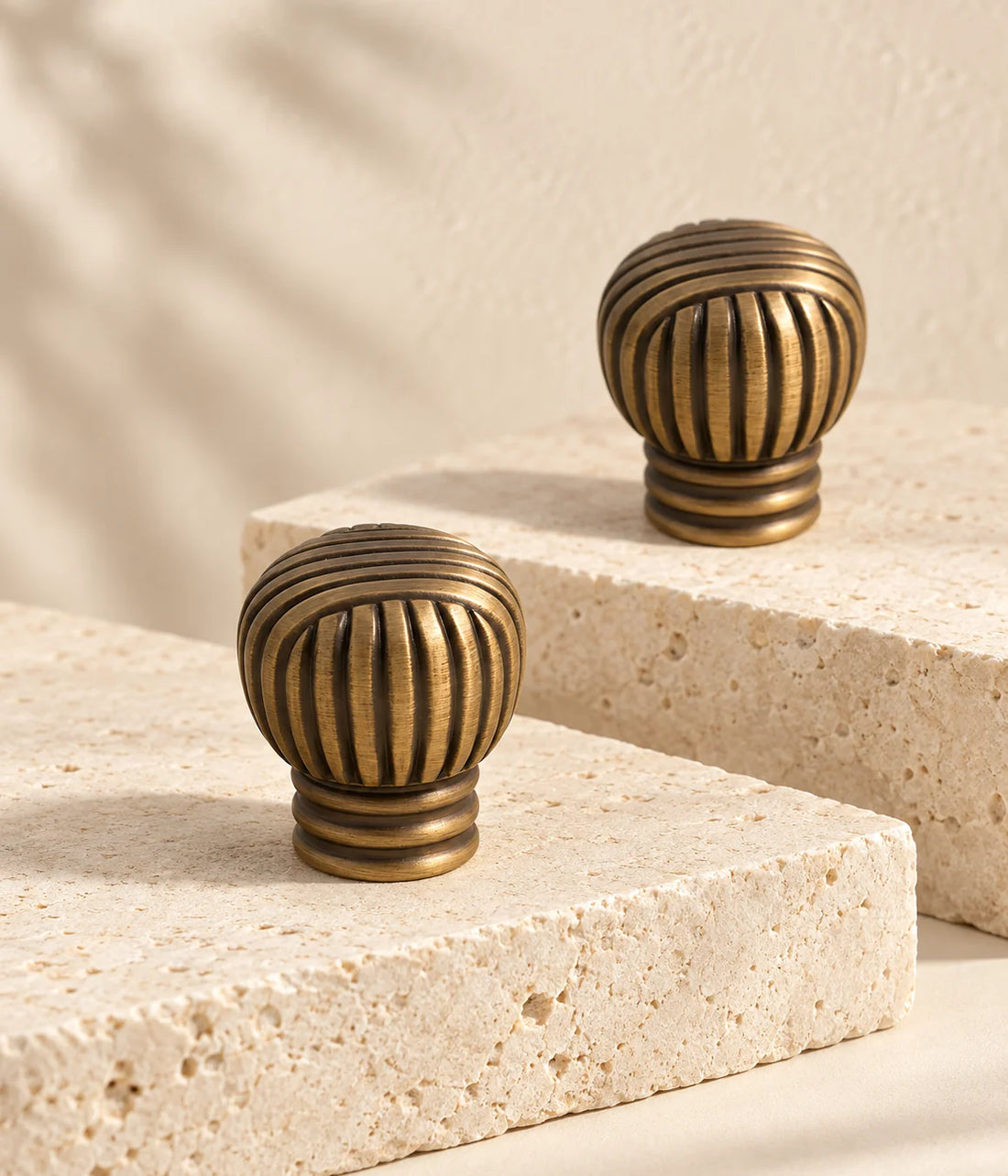 Antique brass cross-ribbed ball cabinet knobs arranged on ivory limestone