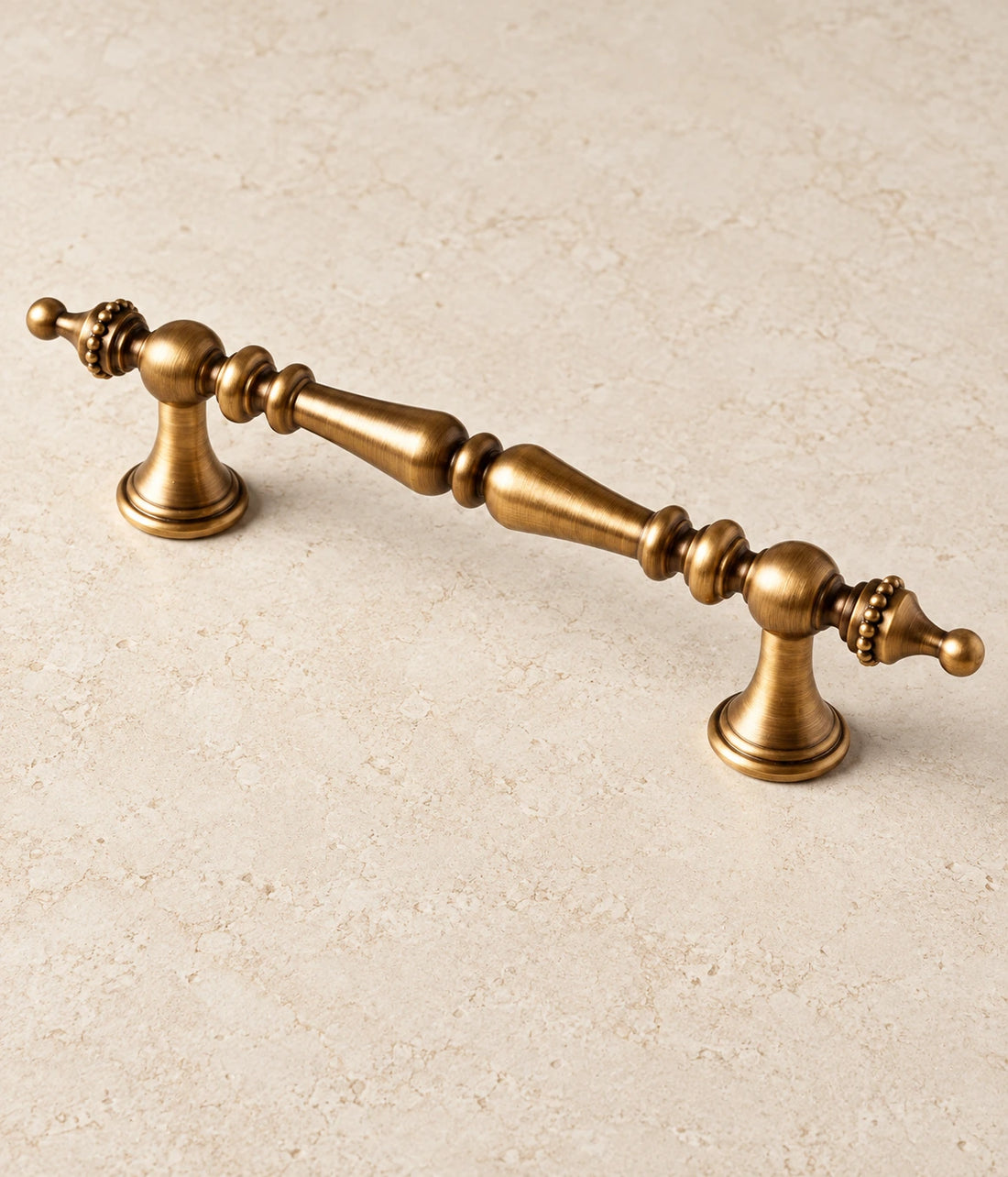 Antique Brass Crown Finial Cabinet Pulls on warm ivory limestone