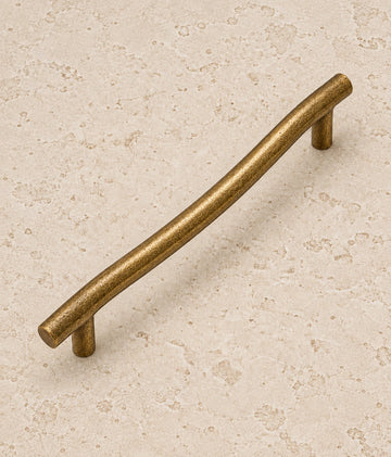 Antique Brass Curved Cabinet Pulls on warm limestone