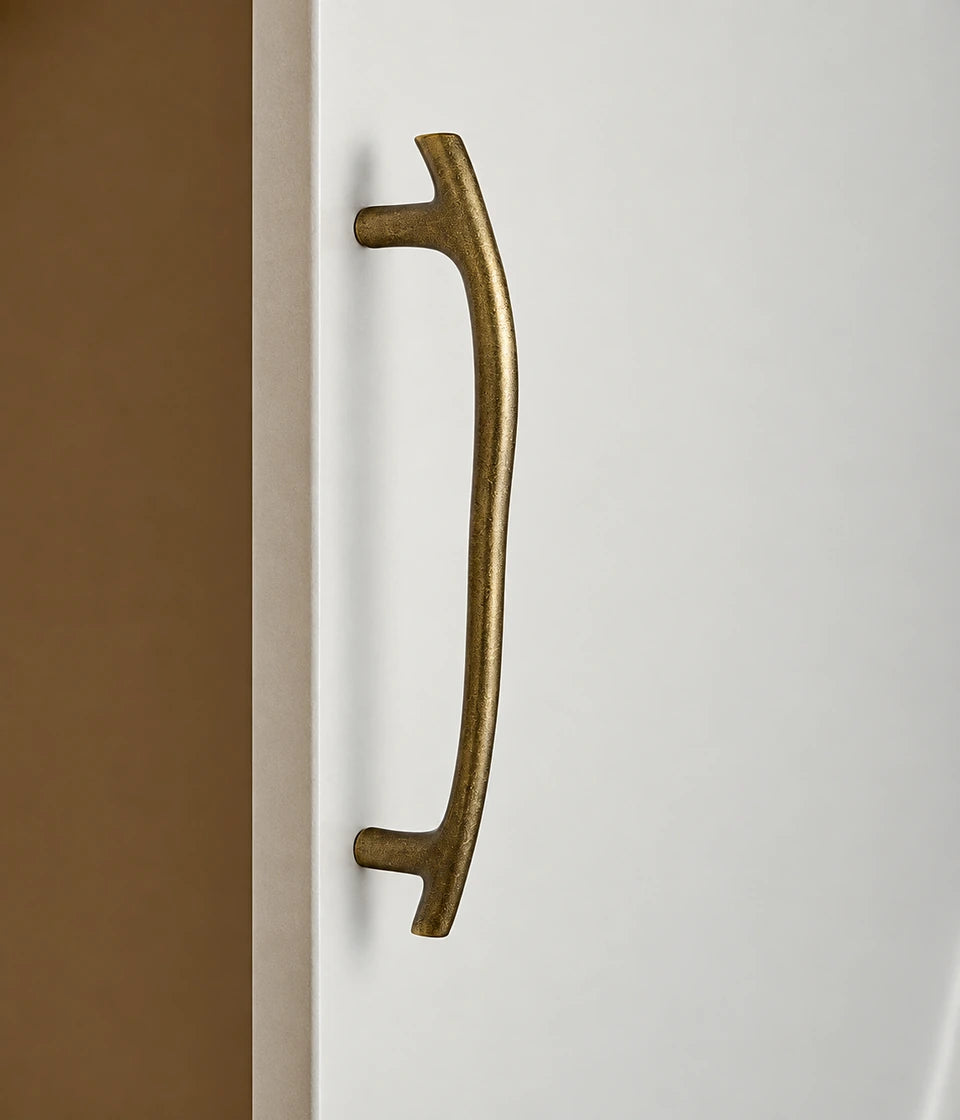 Curved antique brass cabinet pull shown installed