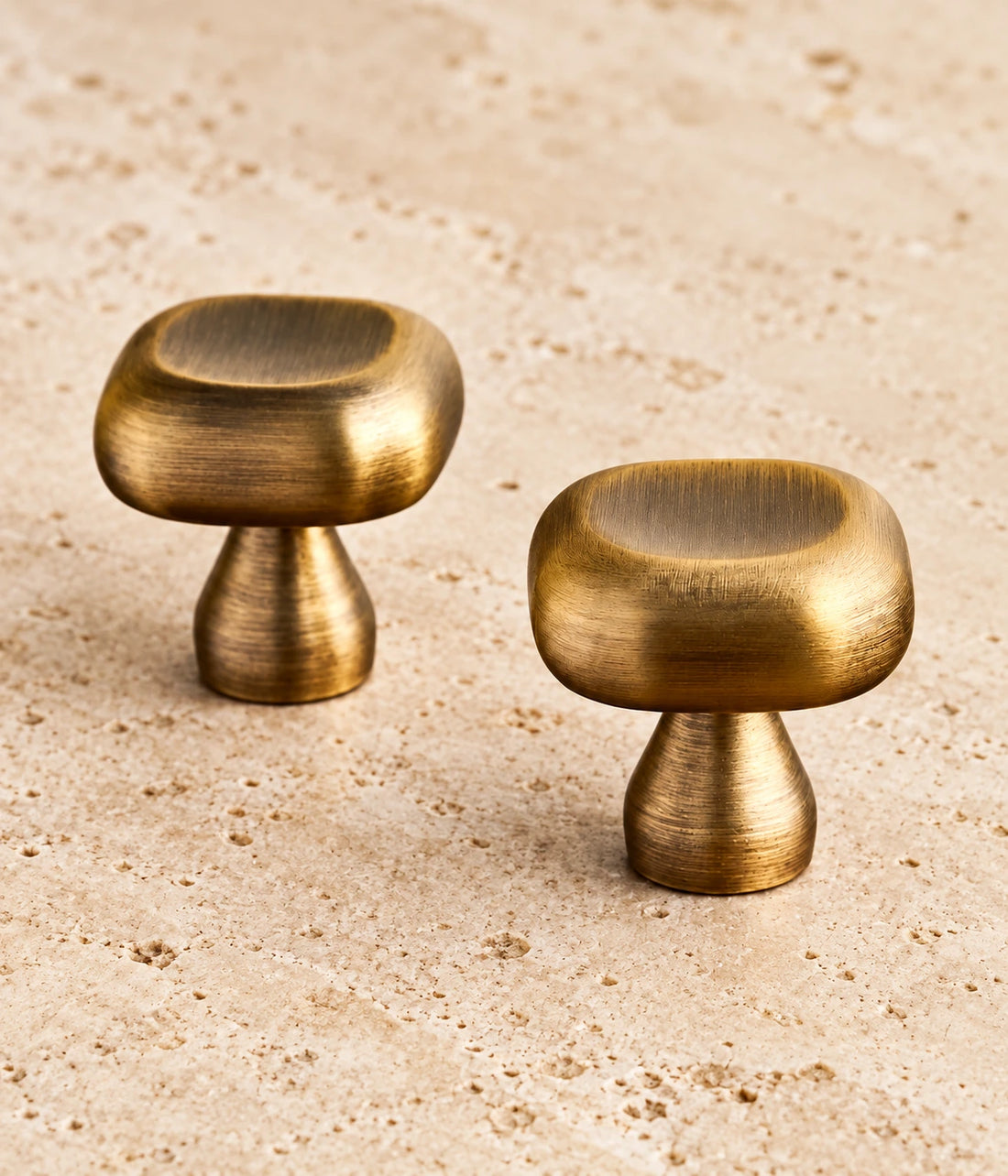 Antique Brass Cushion, Beaded & Floral Cabinet Knobs on warm limestone