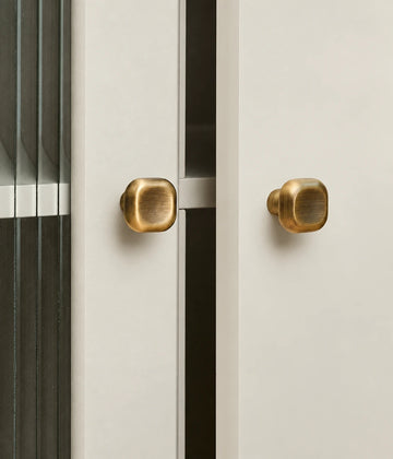 Antique brass cushion cabinet knobs fitted to cream cabinet doors
