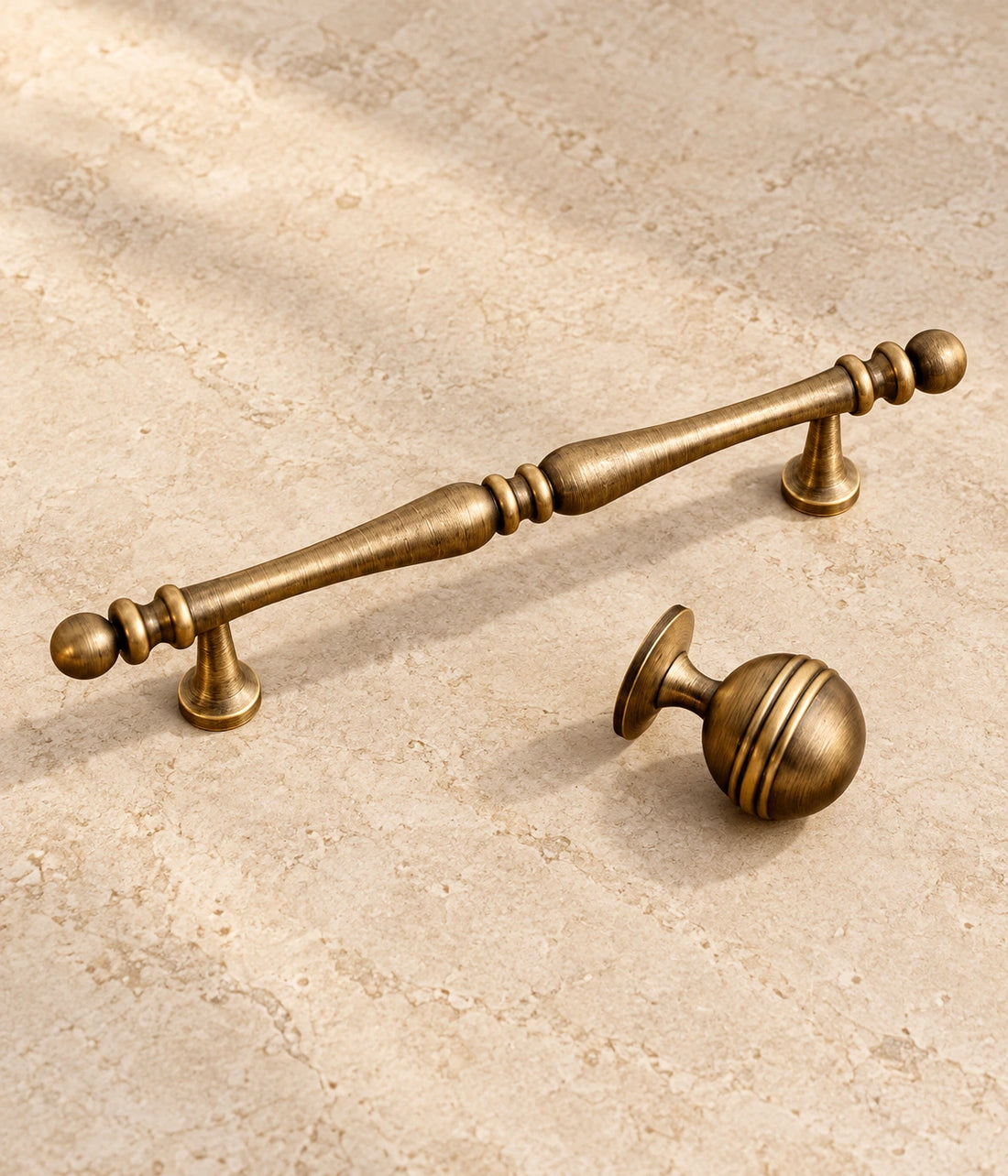 Antique Brass Decorative Cabinet Pulls & Grooved Ball Knobs on warm ivory limestone