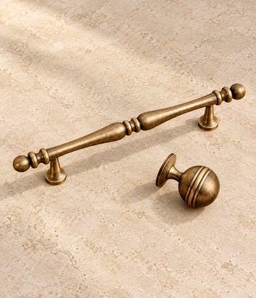 Antique Brass Decorative Cabinet Pulls & Grooved Ball Knobs on warm ivory limestone