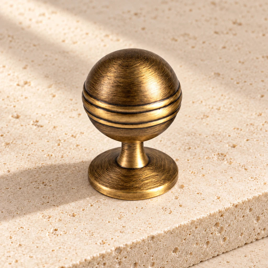 antique brass decorative grooved ball knob limestone on pale limestone.
