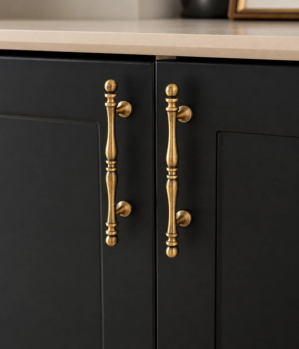 Decorative antique brass cabinet pulls installed vertically on dark cabinet doors