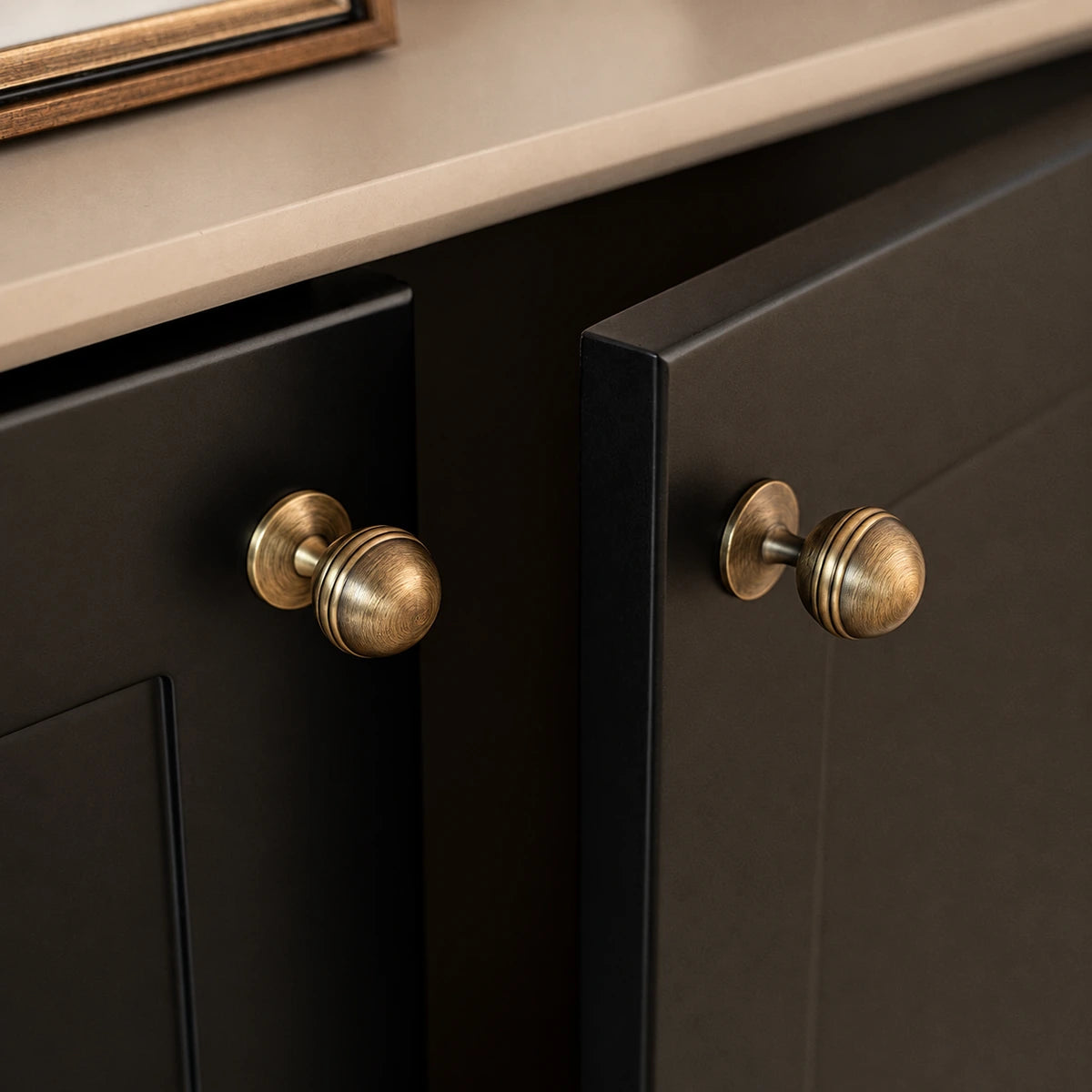 Grooved ball knobs in antique brushed brass installed on cabinet doors