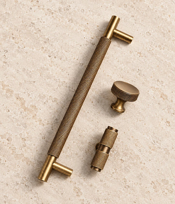 Antique Brass Diamond-Knurled Cabinet Pulls & Knobs on warm ivory limestone
