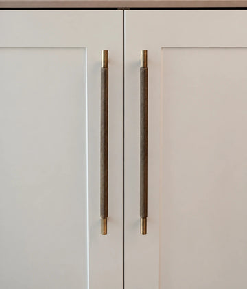 Antique brass diamond-knurled cabinet pulls installed vertically on cream cabinet doors