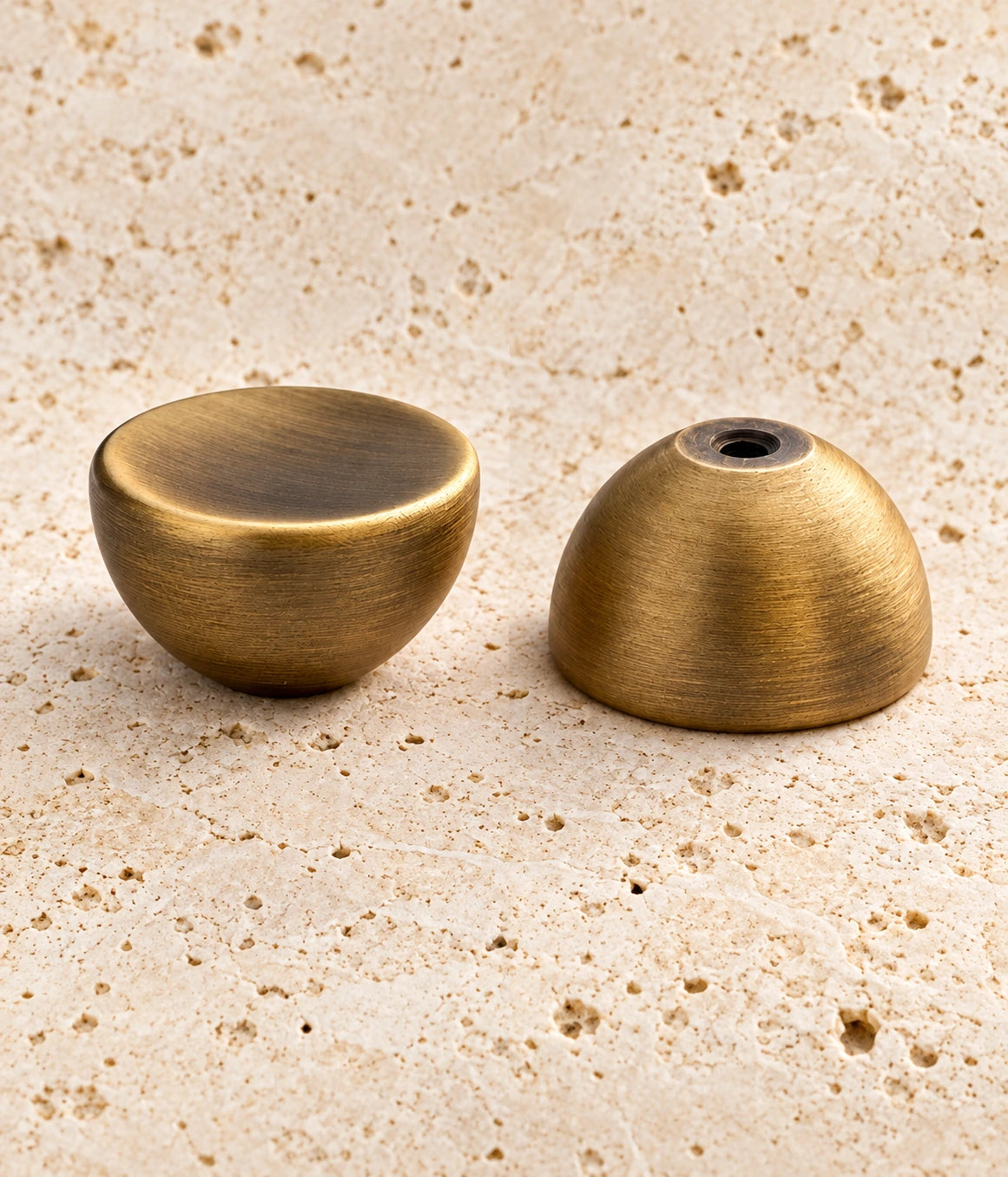 Antique Brass Dished Round Cabinet Knob on warm limestone